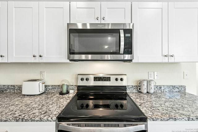 kitchen with light stone countertops, appliances with stainless steel finishes, and white cabinets