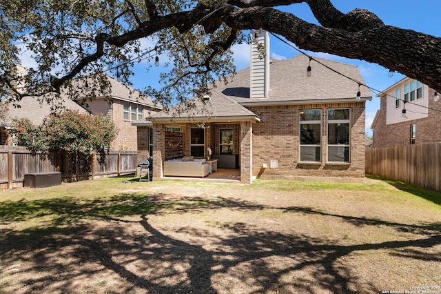 rear view of property with a patio area, a yard, a fenced backyard, and brick siding