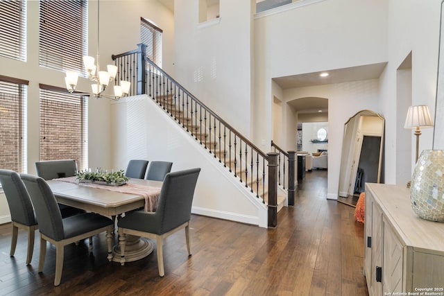 dining space with dark wood-style floors, stairway, arched walkways, and baseboards