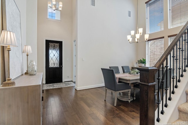 entryway with stairway, dark wood-type flooring, a notable chandelier, and a towering ceiling