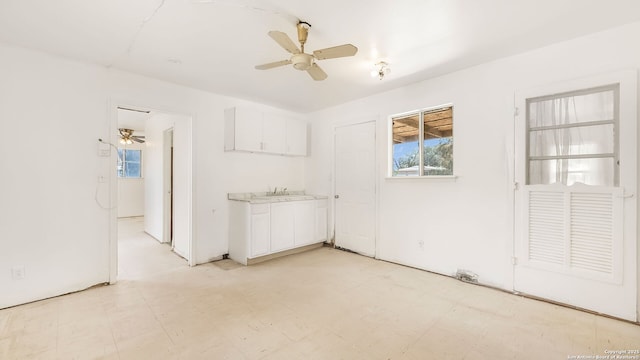 unfurnished room featuring a ceiling fan, light floors, and a sink