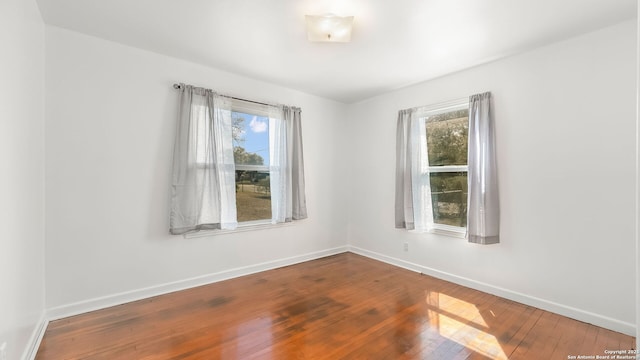 empty room featuring baseboards, a healthy amount of sunlight, and hardwood / wood-style flooring