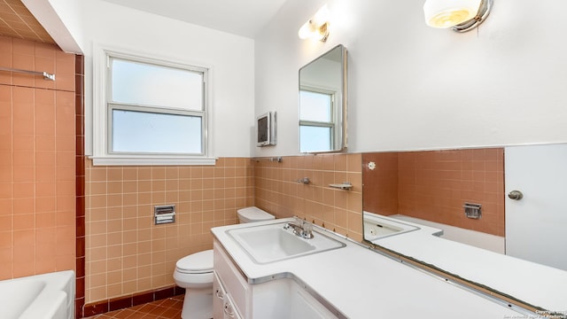 full bath with toilet, tile walls, vanity, and a healthy amount of sunlight