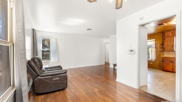 living area with visible vents, wood finished floors, baseboards, and ceiling fan