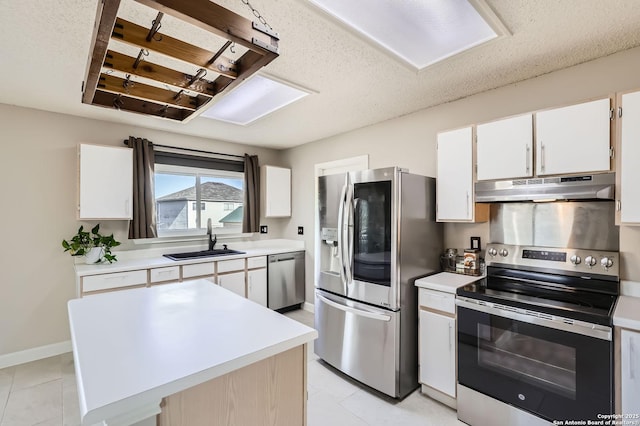 kitchen featuring under cabinet range hood, stainless steel appliances, light countertops, and a sink