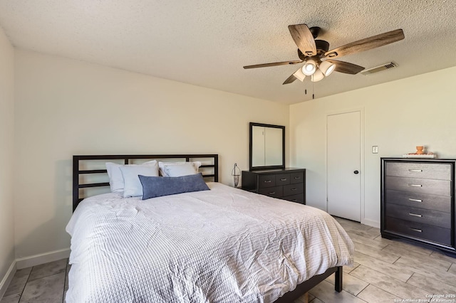 bedroom with light wood-type flooring, visible vents, a ceiling fan, a textured ceiling, and baseboards