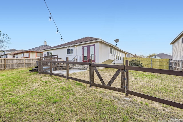 back of property featuring a yard, a fenced backyard, french doors, and a patio area