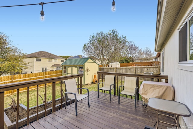 wooden terrace with an outbuilding, a shed, and a fenced backyard