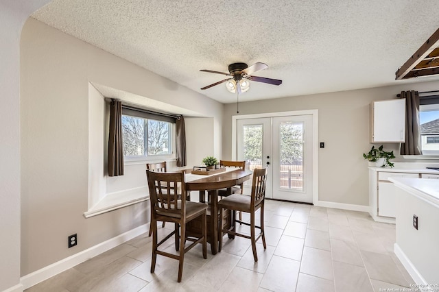 dining space with a ceiling fan, baseboards, light tile patterned flooring, french doors, and a textured ceiling