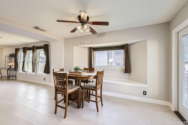 dining room featuring visible vents, ceiling fan, baseboards, light tile patterned floors, and a textured ceiling