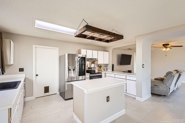 kitchen featuring a center island, light countertops, stainless steel appliances, white cabinetry, and a sink