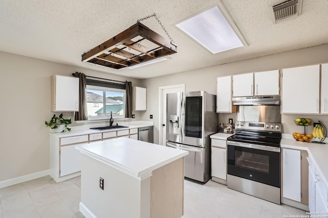 kitchen featuring visible vents, a sink, light countertops, under cabinet range hood, and appliances with stainless steel finishes