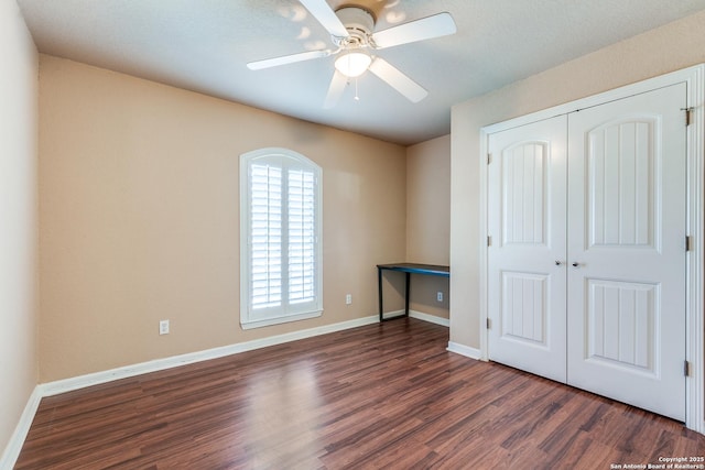 unfurnished bedroom featuring ceiling fan, a closet, baseboards, and wood finished floors