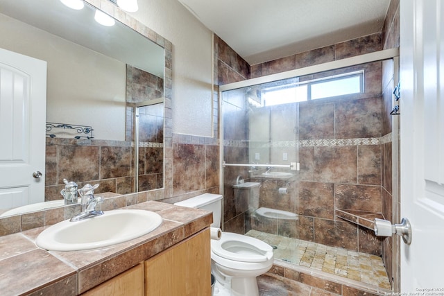 bathroom with vanity, tile walls, toilet, and a shower stall