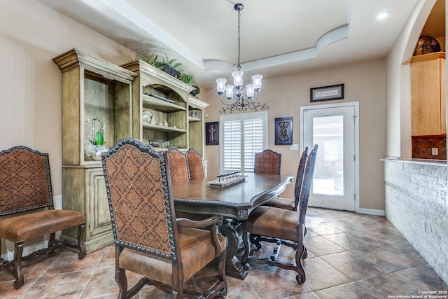 dining area with tile patterned floors, a raised ceiling, and a chandelier