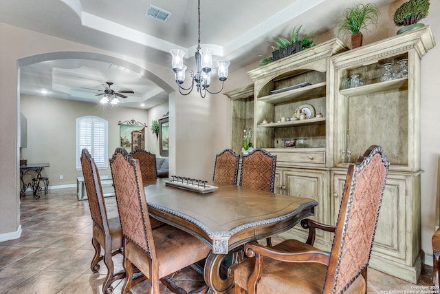 dining area featuring light tile patterned floors, visible vents, a tray ceiling, arched walkways, and ceiling fan with notable chandelier