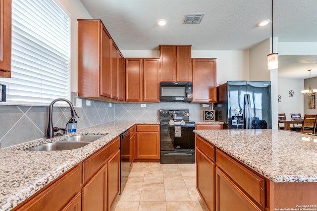 kitchen with light stone counters, brown cabinetry, visible vents, a sink, and black appliances