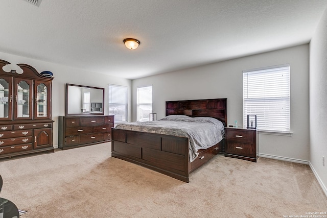 bedroom featuring baseboards, light colored carpet, and a textured ceiling