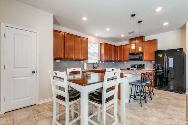 kitchen with brown cabinetry, visible vents, a sink, black appliances, and backsplash