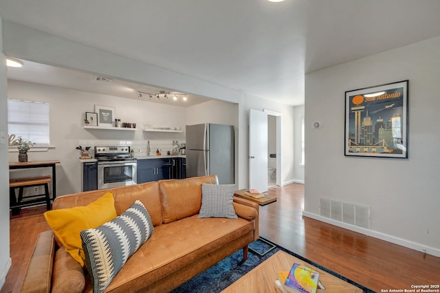 living room with wood finished floors, visible vents, and baseboards