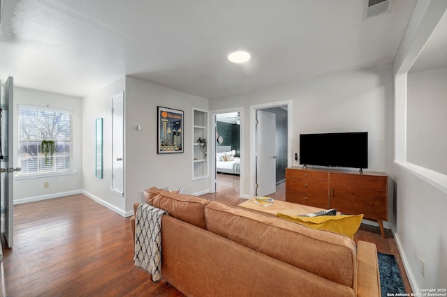 living room with built in features, visible vents, baseboards, and hardwood / wood-style floors