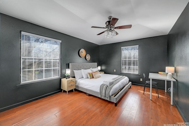 bedroom featuring multiple windows, baseboards, and hardwood / wood-style flooring