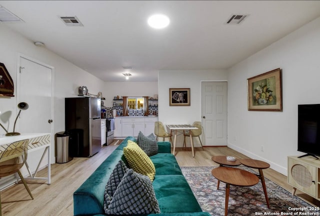 living room featuring visible vents, baseboards, and light wood-style floors