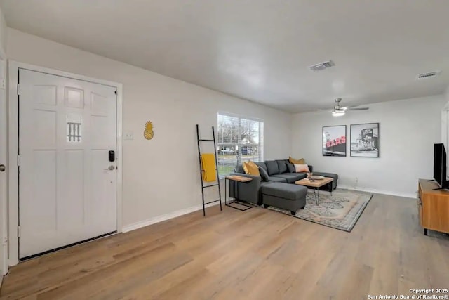 living area featuring light wood-type flooring, visible vents, and baseboards