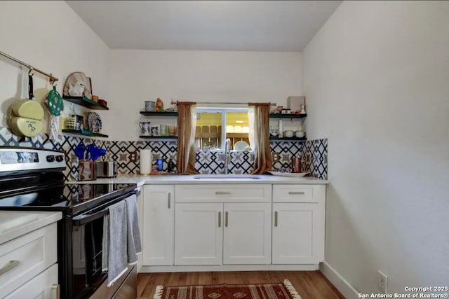 kitchen with open shelves, stainless steel electric range, a sink, light countertops, and white cabinets