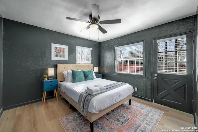 bedroom with light wood-style flooring, multiple windows, a ceiling fan, and baseboards