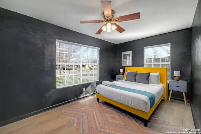 bedroom featuring multiple windows, ceiling fan, and wood finished floors