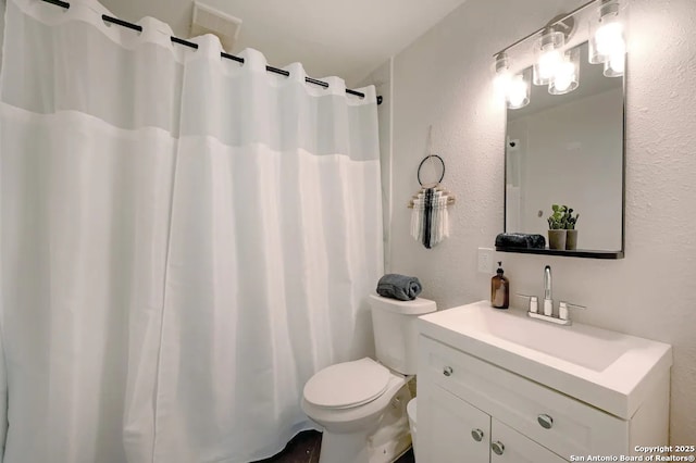 bathroom featuring vanity, a shower with curtain, toilet, and a textured wall