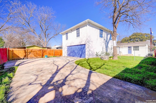 view of side of property with a lawn, driveway, a garage, and fence