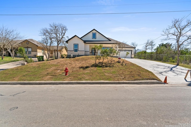 view of front of house featuring an attached garage, concrete driveway, and fence