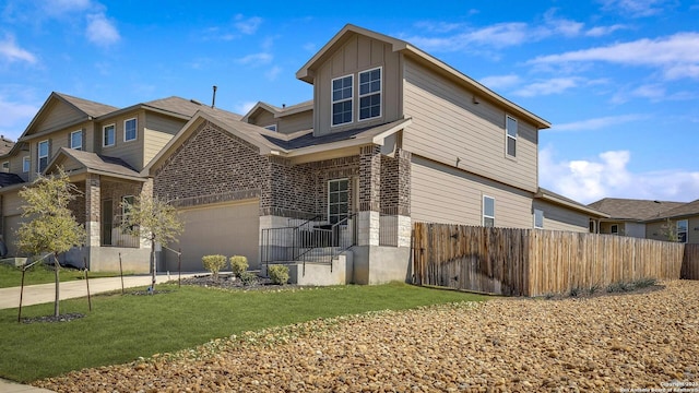 view of home's exterior with a yard, brick siding, board and batten siding, and fence