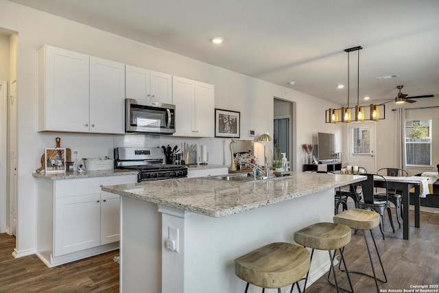6424 Embankment, San Antonio, TX 78252 - kitchen with an island with sink, a kitchen breakfast bar, stainless steel appliances, white cabinets, and dark wood-style flooring