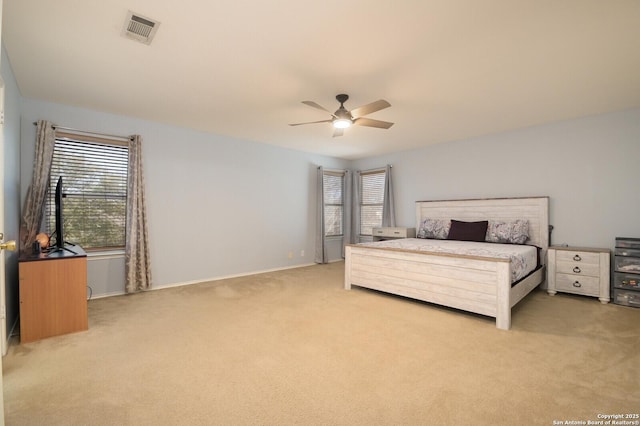 bedroom with visible vents, light colored carpet, baseboards, and ceiling fan