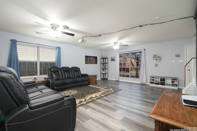 living area featuring visible vents, baseboards, wood finished floors, and a ceiling fan