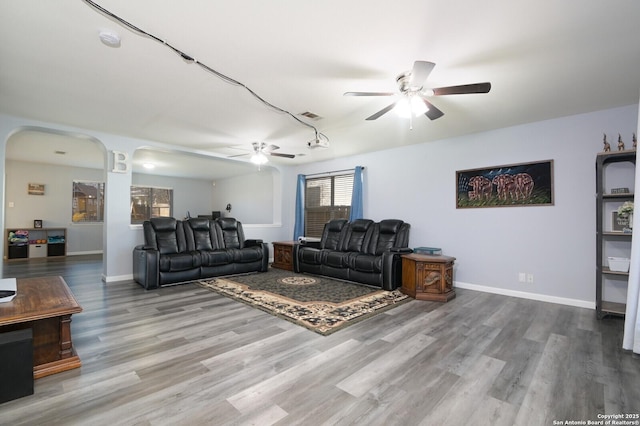 living room with visible vents, wood finished floors, baseboards, and ceiling fan