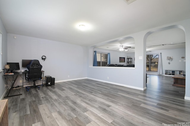 living room featuring ceiling fan, baseboards, arched walkways, and wood finished floors