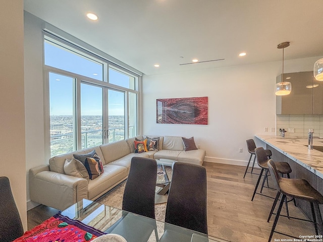 living room featuring recessed lighting, light wood-type flooring, and baseboards