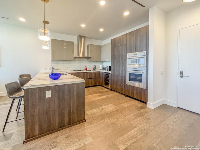 kitchen featuring stainless steel appliances, wine cooler, a kitchen bar, wall chimney range hood, and modern cabinets