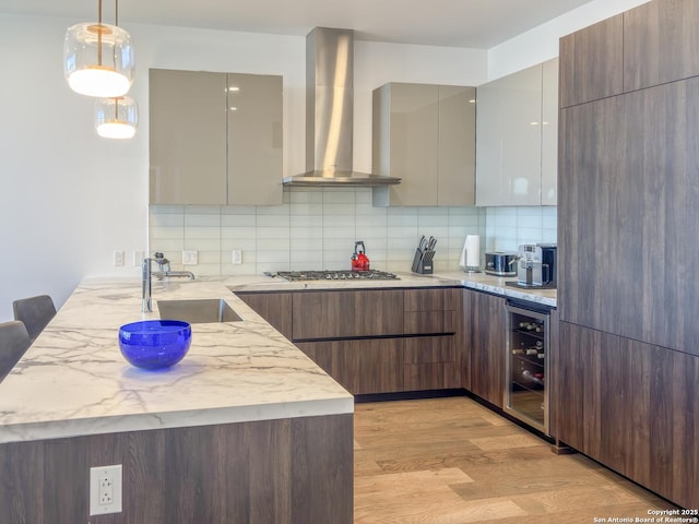 kitchen with beverage cooler, decorative backsplash, a peninsula, modern cabinets, and wall chimney exhaust hood