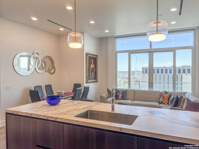 kitchen with a view of city, pendant lighting, a sink, light stone counters, and open floor plan