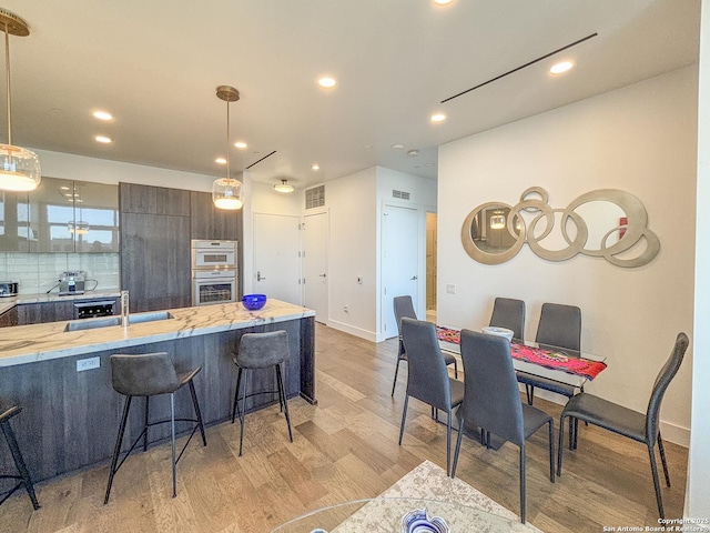 kitchen featuring decorative light fixtures, a breakfast bar area, light wood-style floors, and modern cabinets