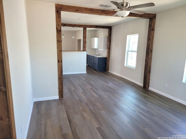 interior space featuring baseboards, visible vents, dark wood-style flooring, a sink, and beamed ceiling