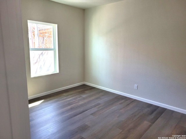 spare room featuring baseboards and dark wood-style flooring