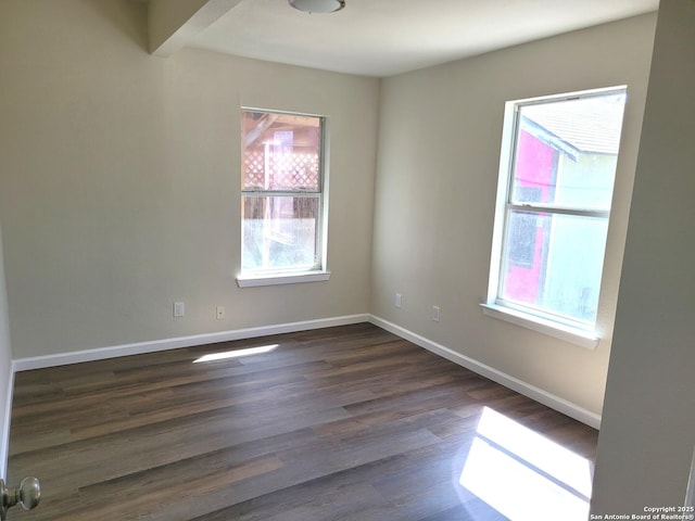 unfurnished room with baseboards and dark wood-style floors