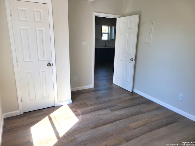 unfurnished bedroom with dark wood-type flooring, baseboards, and a sink