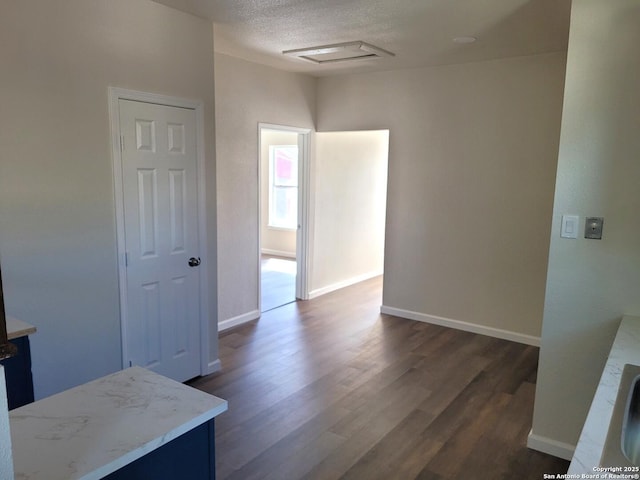 interior space with baseboards, dark wood-type flooring, and a textured ceiling